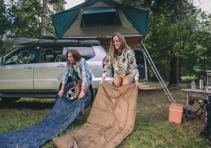 young-women-placing-sleeping-bags-over-the-grass-YLK46MZ.jpg
